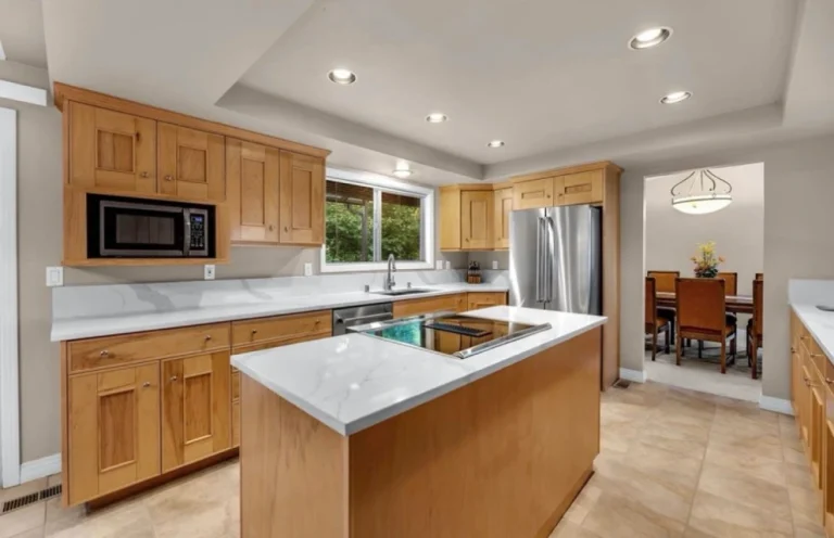 Kitchen with wood cabinets, white countertops, and island with built-in sink – interior gallery photo