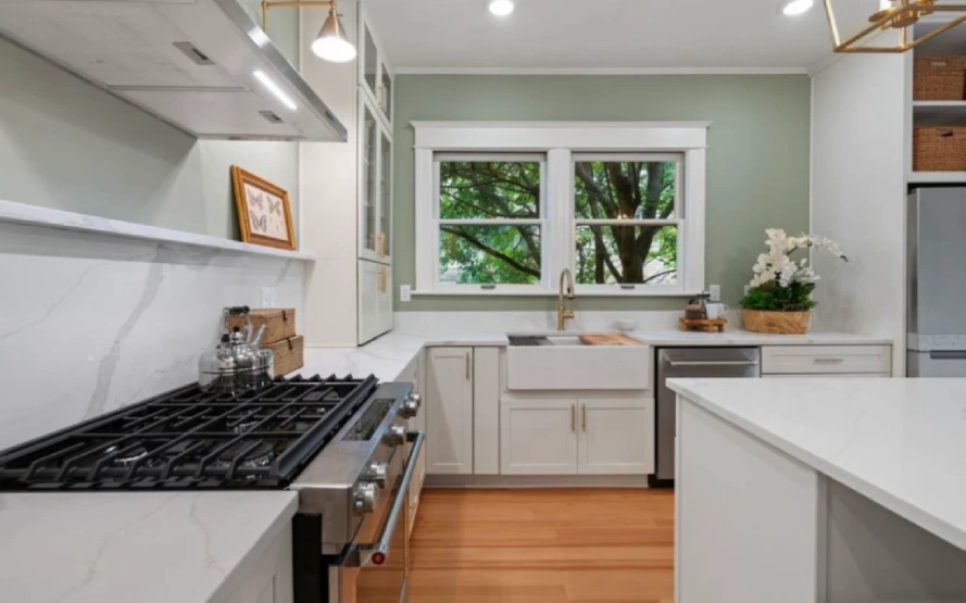 Green kitchen wall with white cabinets, sink, and stove – interior design detail